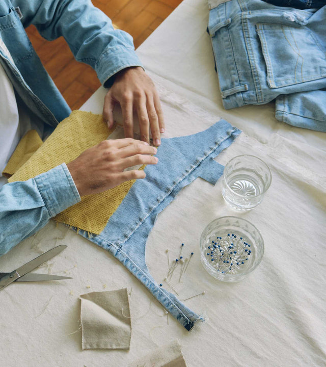 homem-segurando-calça-jeans-upcycling-vestindo-jaqueta-jeans